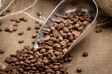 Çuval bezinde demir kaşıkta kahve çekirdeği. Kahvenin aroması, seçilmiş fasulyeler, Arabika, enerji, rahatlama, zevk..