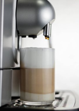 Kahve makinesi beyaz arka planda cam bir şişede latte yapıyor. Kahveyle sütü karıştırıyorum. Cappuccino, yemek, fincan, sabah, kahvaltı, buhar, sıcak içecek, demleme
