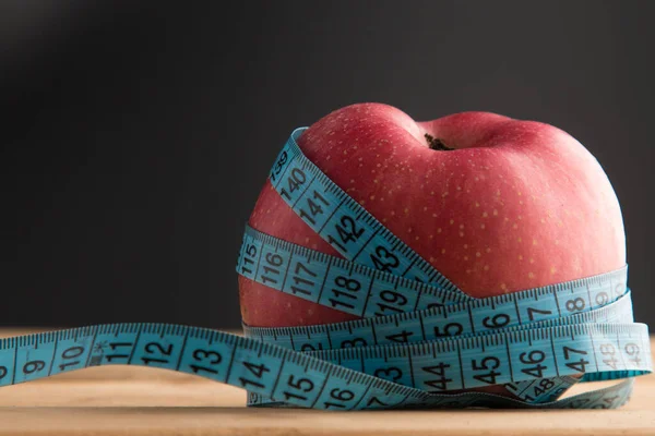 Healthy fruits for the body. An apple and a centimeter to measure the body. Sports, fitness, vitamins, healthy nutrition, fruits, apples, diet, slimming