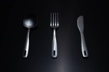 Karanlık bir arka planda çatal bıçak takımı. Çatal, kaşık, bıçak, yemek, aletler, hazırlık