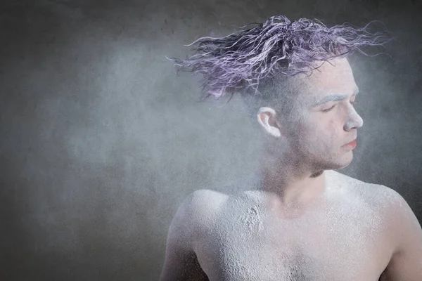 Portrait of a man with purple hair in flour on a gray background. Flying flour. Creative, unusual, vogue, glamor, purple hair, pose, fashion, art