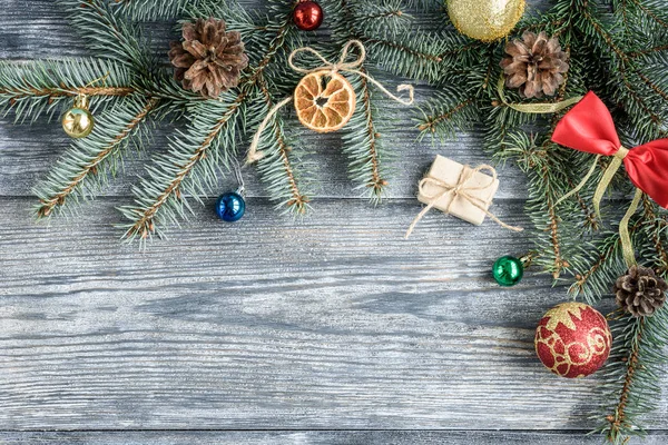 Noel veya Yeni Yıl dekorasyonu arka planında köknar dalları, koniler, toplar, marşmelovlar gri ahşap tahtada.