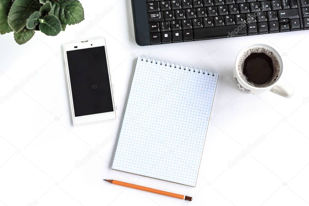 A notepad with smart phone, pencil and coffee on white table with copy space. Flatlay.