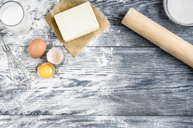 Fırın malzemeleri - un, yumurta, tereyağı, süt, şeker ve gri ahşap masa. Ev yapımı fırın..