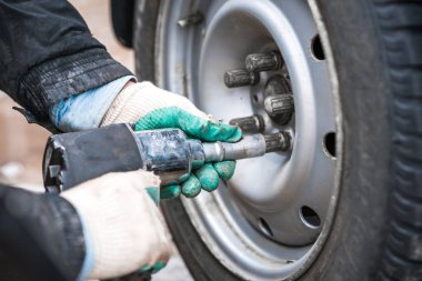 Pnömatik ingiliz anahtarıyla arabanın tekerini değiştirin. Arabayı tamir et.