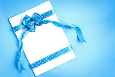 Puantiyeli mavi kurdeleli boş bir kağıt not ve mavi arkaplanda eğilme..