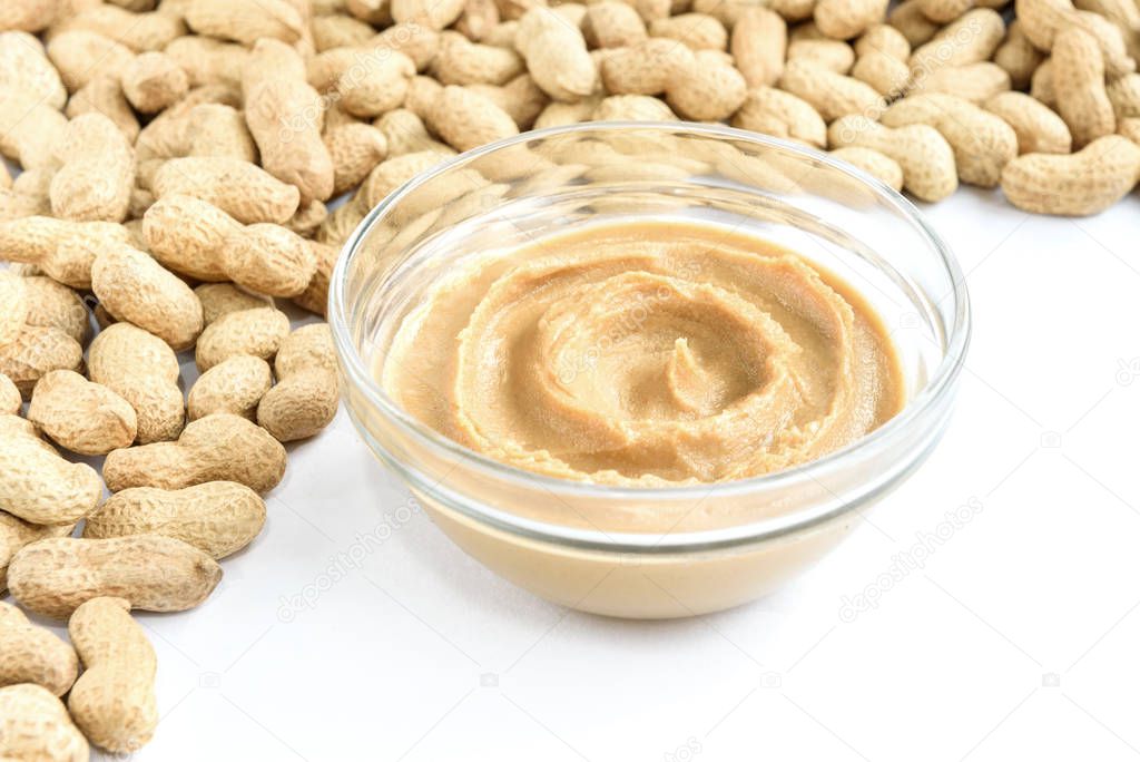 Peanut butter and peanuts on white background.