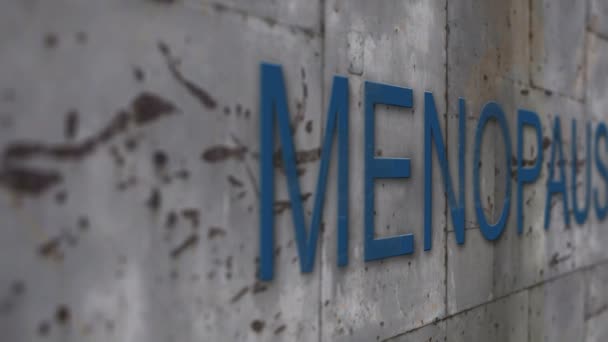 Закрыть металлическую стену со словом менопауза — стоковое видео
