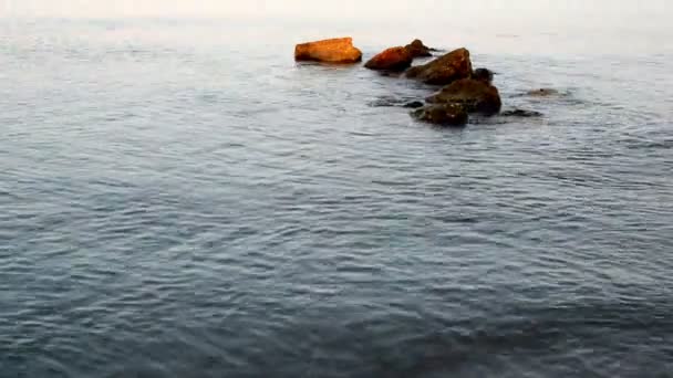 Primer plano de pequeñas olas sobre rocas en la orilla de la playa de arena blanca — Vídeos de Stock