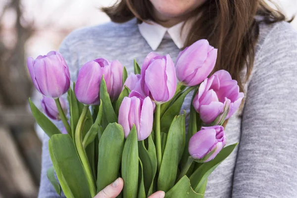 Bukett med lila tulpaner i händerna på en flicka — Stockfoto