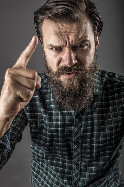 灰色の背景に彼の指で脅かす怒っている髭の男のポートレート クローズ アップ — ストック写真