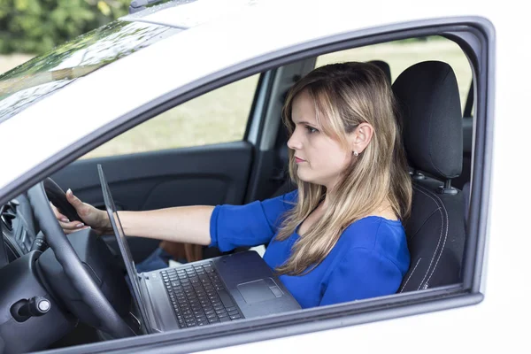 年轻妇女开车时在车里用笔记本电脑 安全驾驶概念 — 图库照片