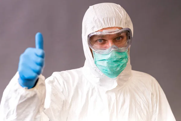 Male Doctor Surgical Mask Goggles Protective Suit Pointing Okay Gray — Stock Photo, Image