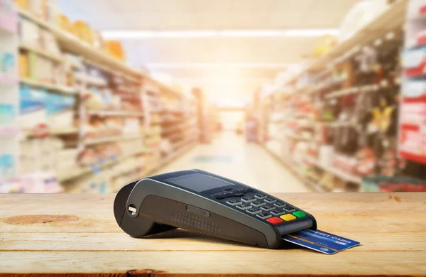 Credit card machine on wood with supermarket background