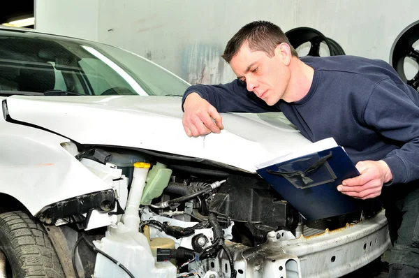 Mechanic inspecting car body damage at auto repair shop service — Stock Photo, Image