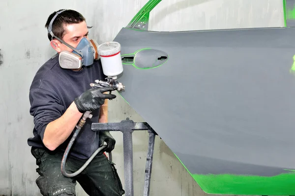 Pintor de coches profesional trabajando en una puerta verde . — Foto de Stock