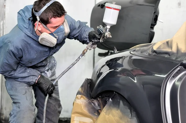 Pintor de coches profesional trabajando en un vehículo negro . — Foto de Stock