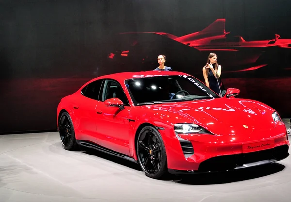 Röd Porsche Taycan turbo, på scen med två vackra flickor. — Stockfoto