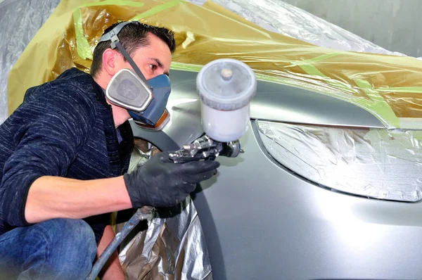 Un trabajador guapo pintando un coche. Ningún modelo mecánico real . —  Fotos de Stock