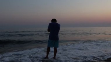 Gün batımında sahilde depresif bir adamın silueti.