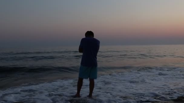 日没時にビーチで悲しい落ち込んでいる男のシルエット — ストック動画