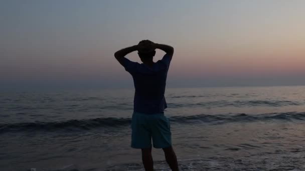 Силуэт грустного депрессивного мужчины на пляже во время заката — стоковое видео
