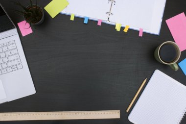 Dizüstü bilgisayarı, yüzey kitabı, kırtasiyesi ve bir fincan kahvesi olan bir masa.