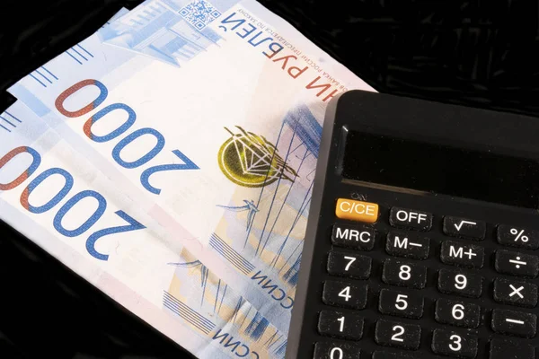 Siyah arkaplanda hesap makinesi olan iki bin ruble banknot.