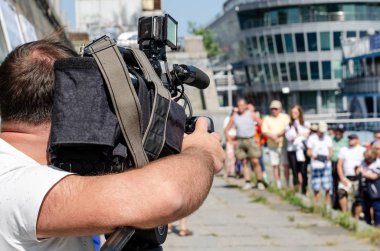 Videograf, sokaktaki insanların güneşteki fotoğraflarını çekiyor.