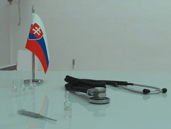 Şırınga, COVID 19 koronovirüs aşısı ve fonendoskop Slovakya 'daki bir sağlık masasında..
