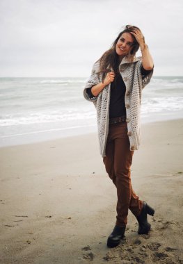 Bir deniz kumsalda yürüyen genç şık hipster kadın sonbahar yaşam tarzı moda portre sevimli trendy kıyafeti giymiş, hafta sonları zevk ve seyahat