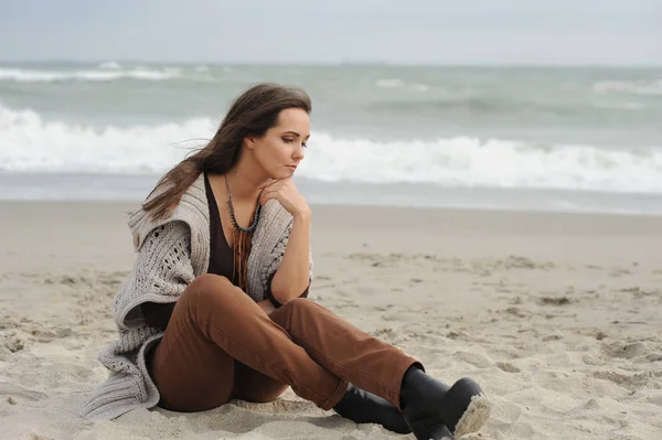 Λυπημένη γυναίκα που κάθεται σε μια παραλία στη θάλασσα — Φωτογραφία Αρχείου