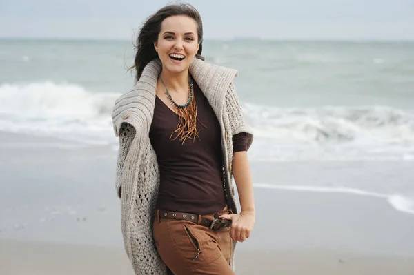 Junge lächelnde Frau, die an einem Strand am Meer spaziert, Herbstmode, heilen — Stockfoto