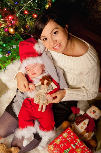 Pasgeboren baby in Santa kleren slapen op een moeder handen — Stockfoto