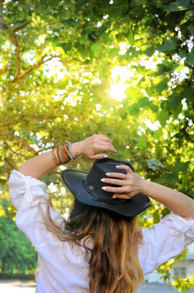 Giovane donna in stile hipster hanno un riposo nel parco cittadino, giornata di sole, cappello nero in pelle, senza volto — Foto Stock