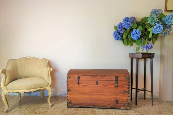 old wooden chest, antique armchair, vase with blue hydrangea