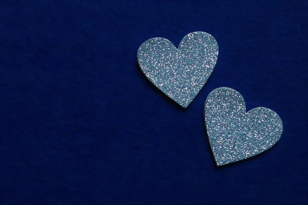 Twee zilveren hartjes op blauwe achtergrond in trendy kleur van jaar 20 — Stockfoto