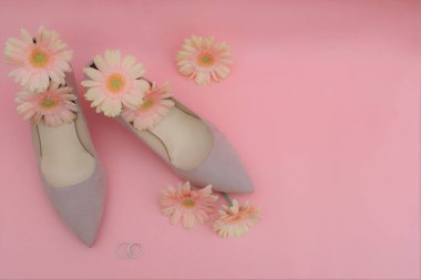 Düğün konsepti. Gerbera çiçekleri, yüzükler, pembe bir b üzerinde bej ayakkabılar.