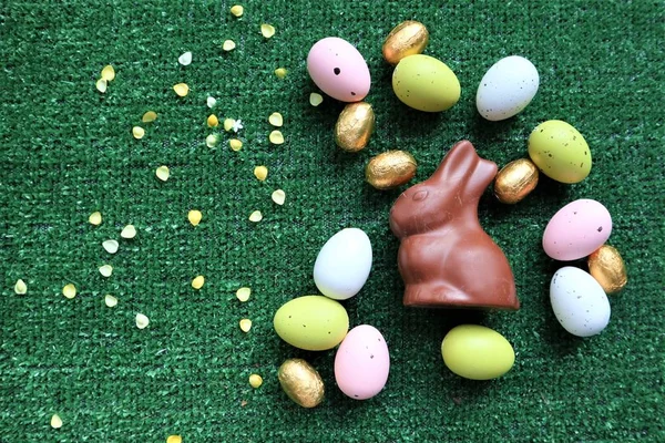 Huevos de Pascua dorados y conejito de chocolate sobre un fondo verde —  Fotos de Stock
