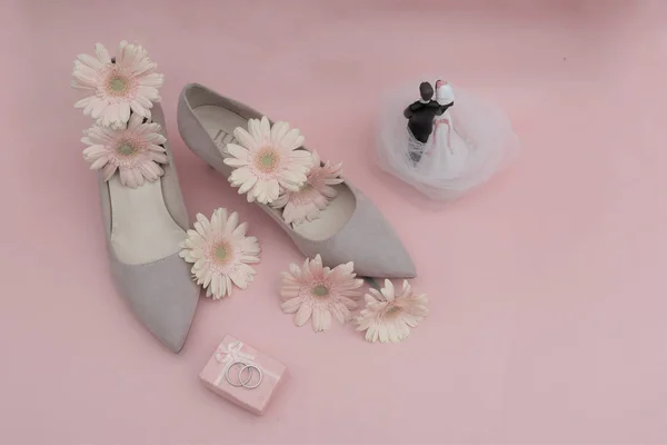 Düğün konsepti. Gerbera çiçekleri, yüzükler, bej ayakkabılar, yeni evliler.