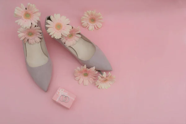 Свадебная концепция. Цветы герберы, кольца, бежевые туфли на розовом — стоковое фото