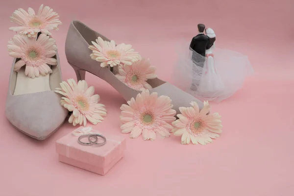 Düğün konsepti. Gerbera çiçekleri, yüzükler, bej ayakkabılar, yeni evliler.