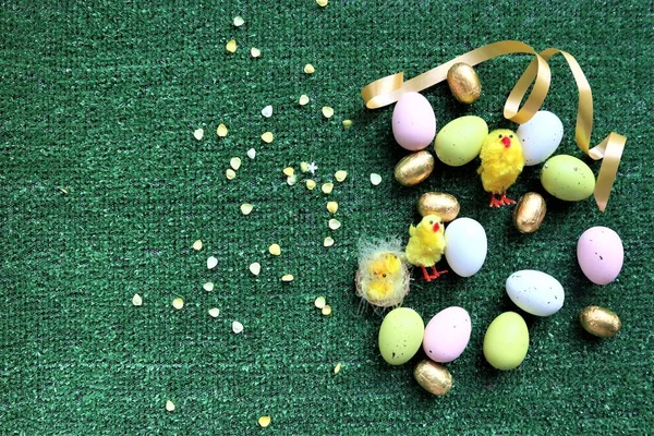 Золотые пасхальные яйца и куры на зеленом фоне — стоковое фото