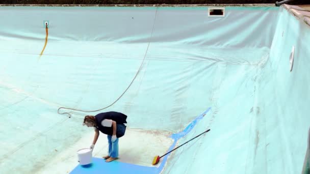 老太婆心不在焉地修理她的游泳池 漂亮的女人用蓝色油漆把游泳池的地板涂成蓝色 — 图库视频影像