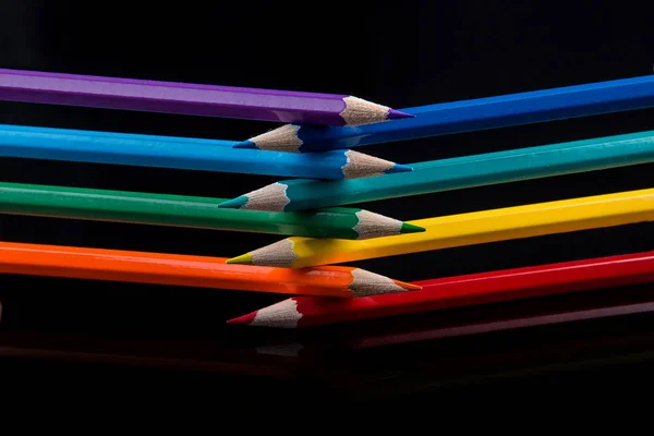 Colored pencils on black background reflected in water. — Stock Photo, Image