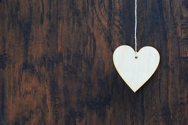 Corazón de madera contrachapada colgando del tendedero. Sobre fondo de madera vieja —  Fotos de Stock