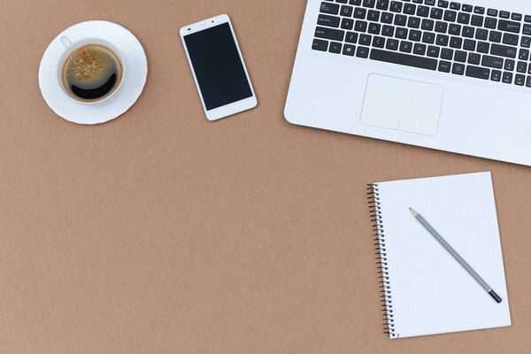 Office table with notepad, computer and coffee cup.