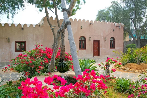 Casa de pedra tradicional e bem no jardim da frente na aldeia Heritage, Abu Dhabi, Emirados Árabes Unidos . — Fotografia de Stock