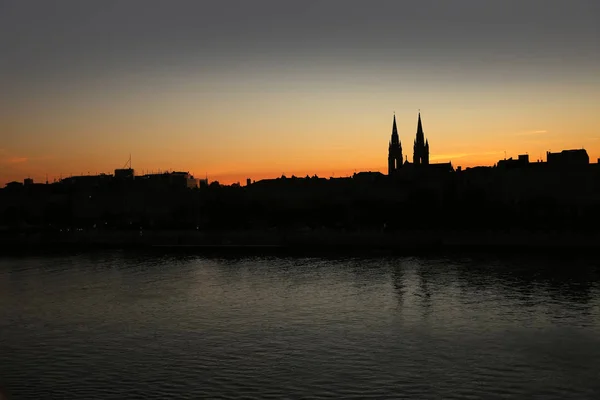 Silhouette of the skyline of the city of Bordeaux, at sunset with church steeples & the river Garonne in the foreground, France. — Stock Photo, Image
