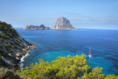 Ibiza 'nın güney kıyısından Es Vedra adasını görüyoruz. Uçurumları ve turkuaz suları olan güzel bir manzara. Balerik Adaları, İspanya.